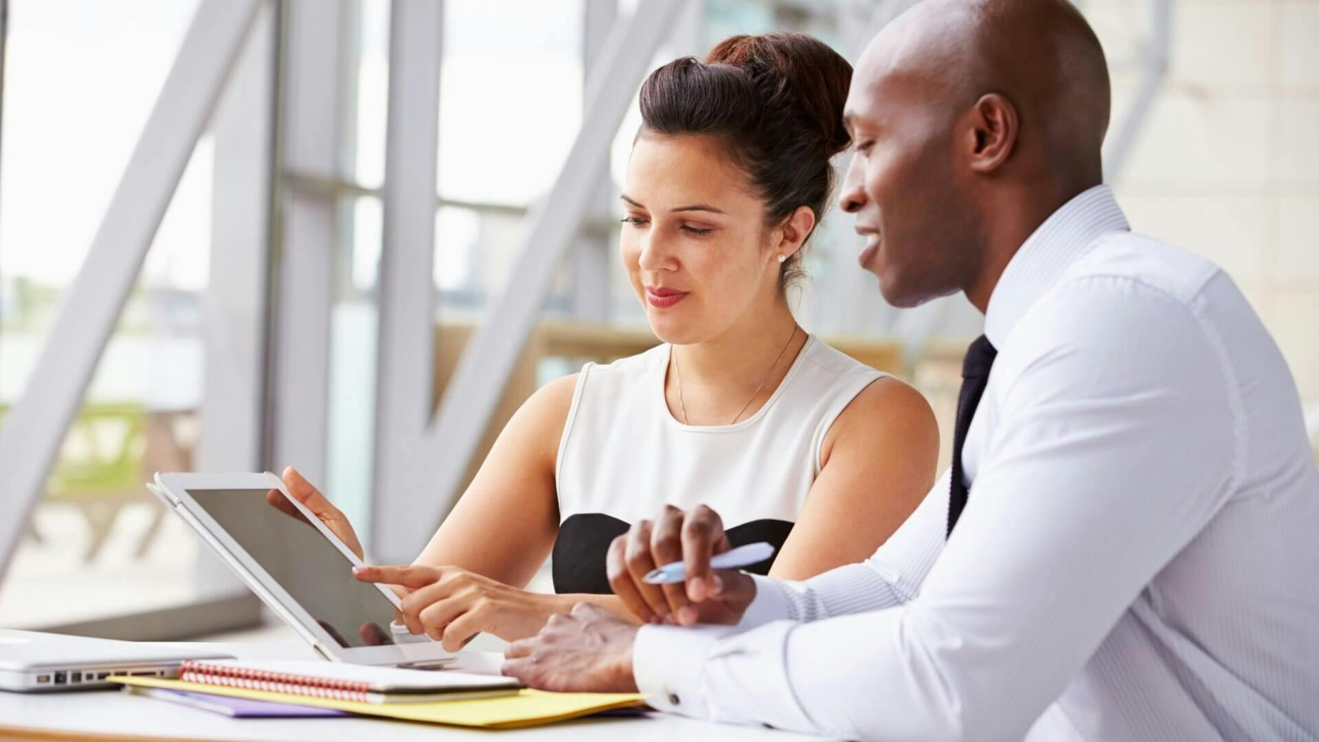 woman presenting a report from a tablet to a man