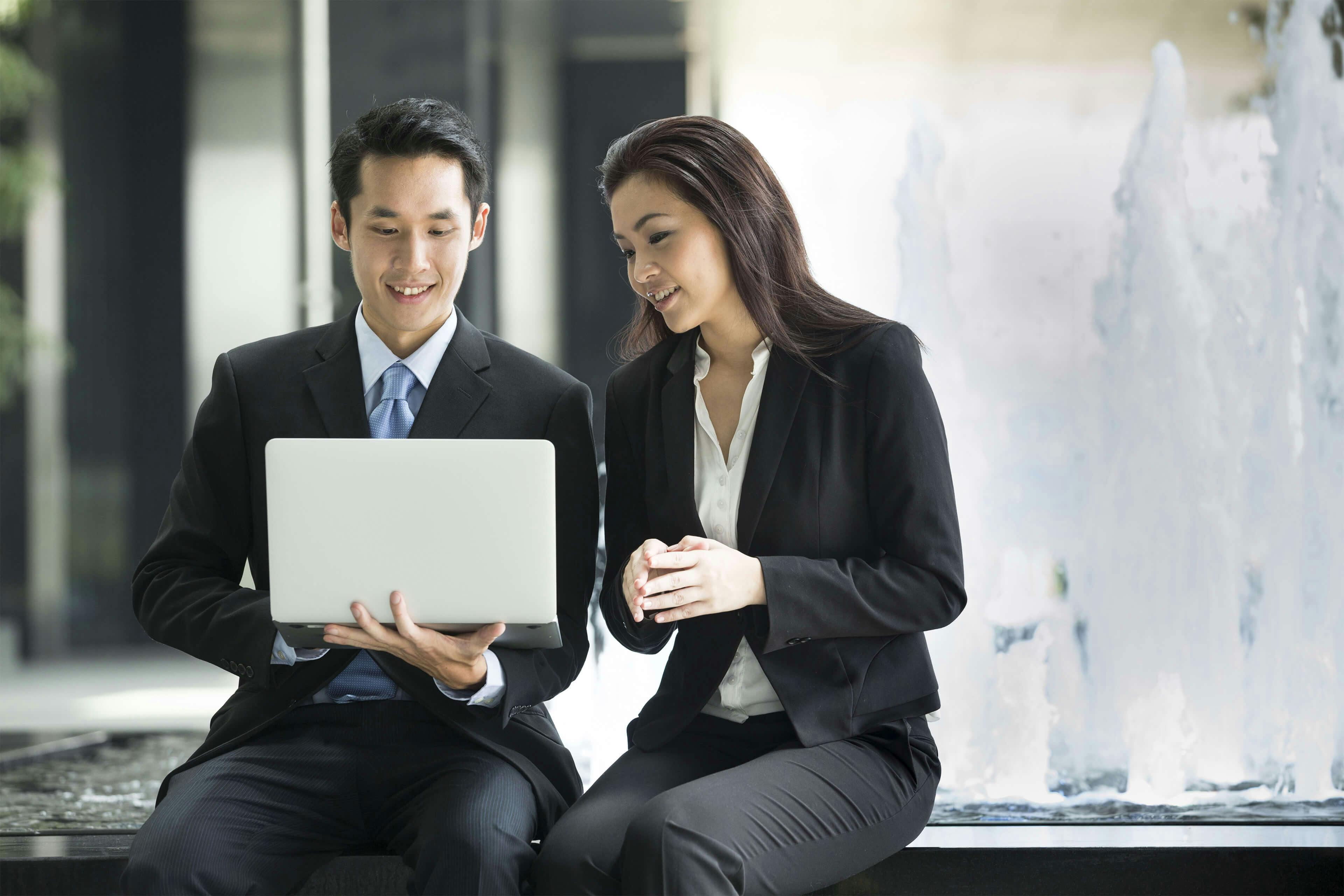 man showing his laptop to a woman