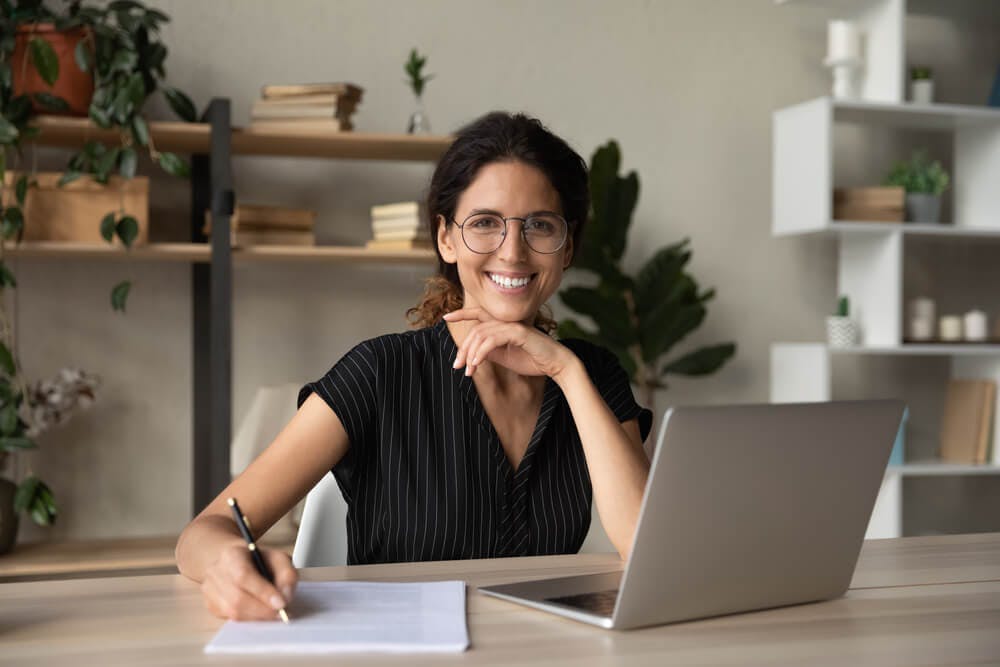 Woman smiling while writing down her personal and professional goals