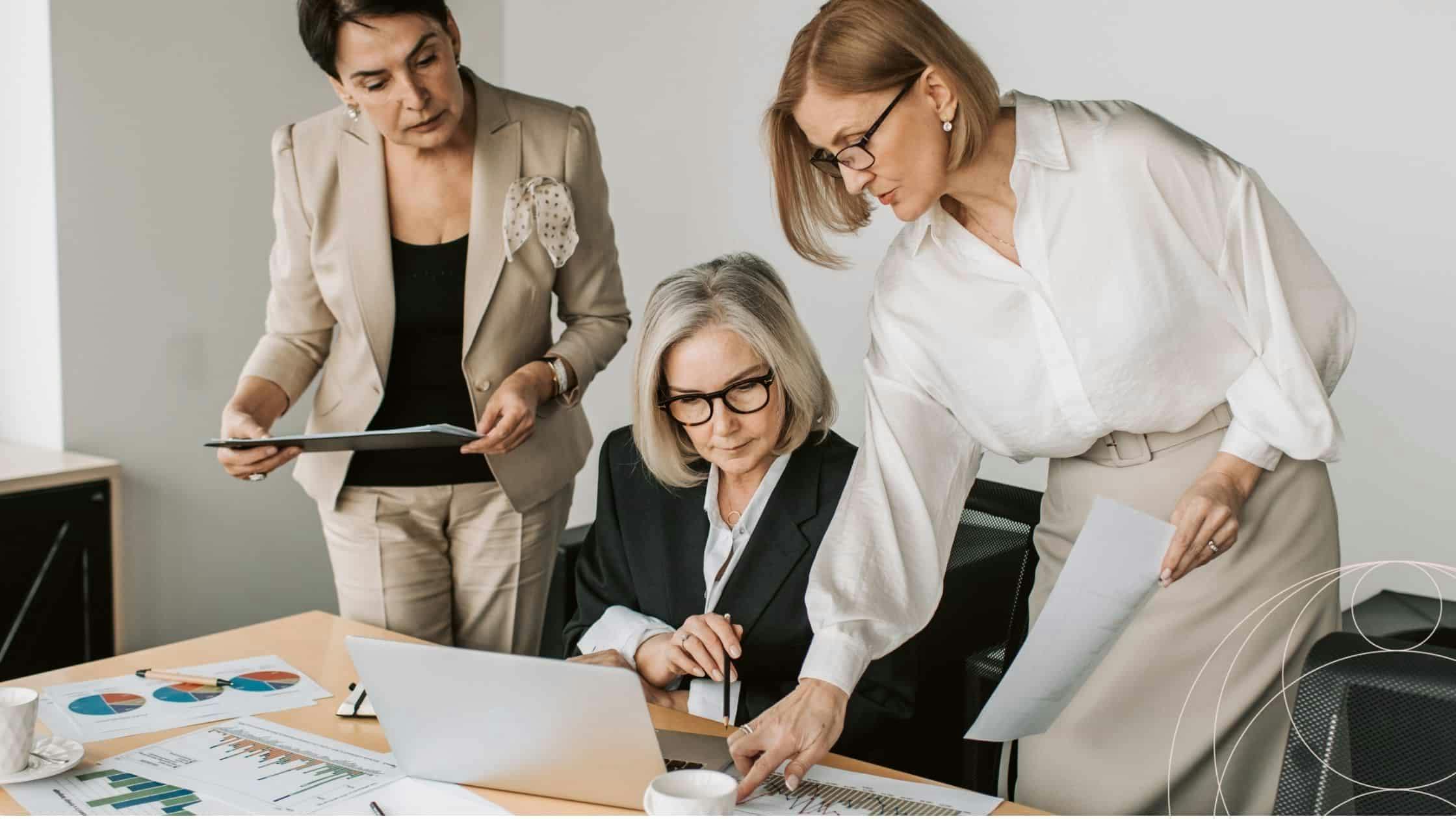 Three leaders around a desk looking at a laptop screen 