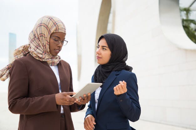 two women wearing head scarfs talking to each other