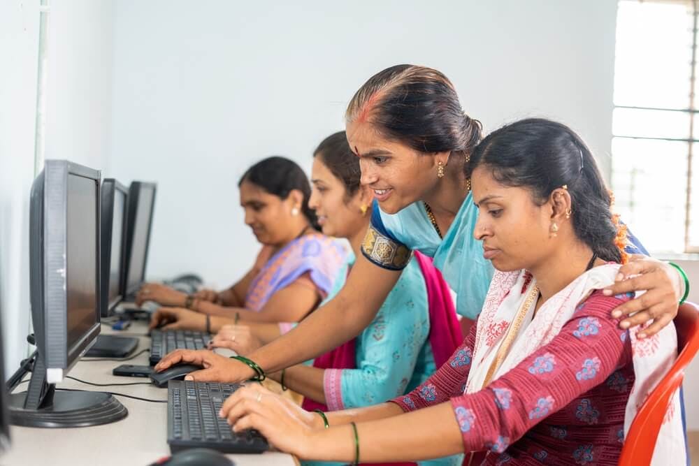 facilitator offering personal support on an employee in front of a computer