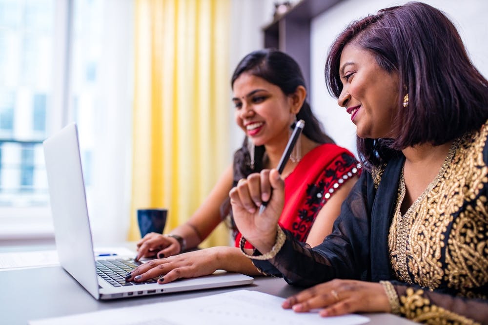two women discussing ideas in front of a laptop