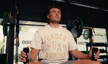 Athlete holding Bolt X1 palm cooling devices in a gym between sets
