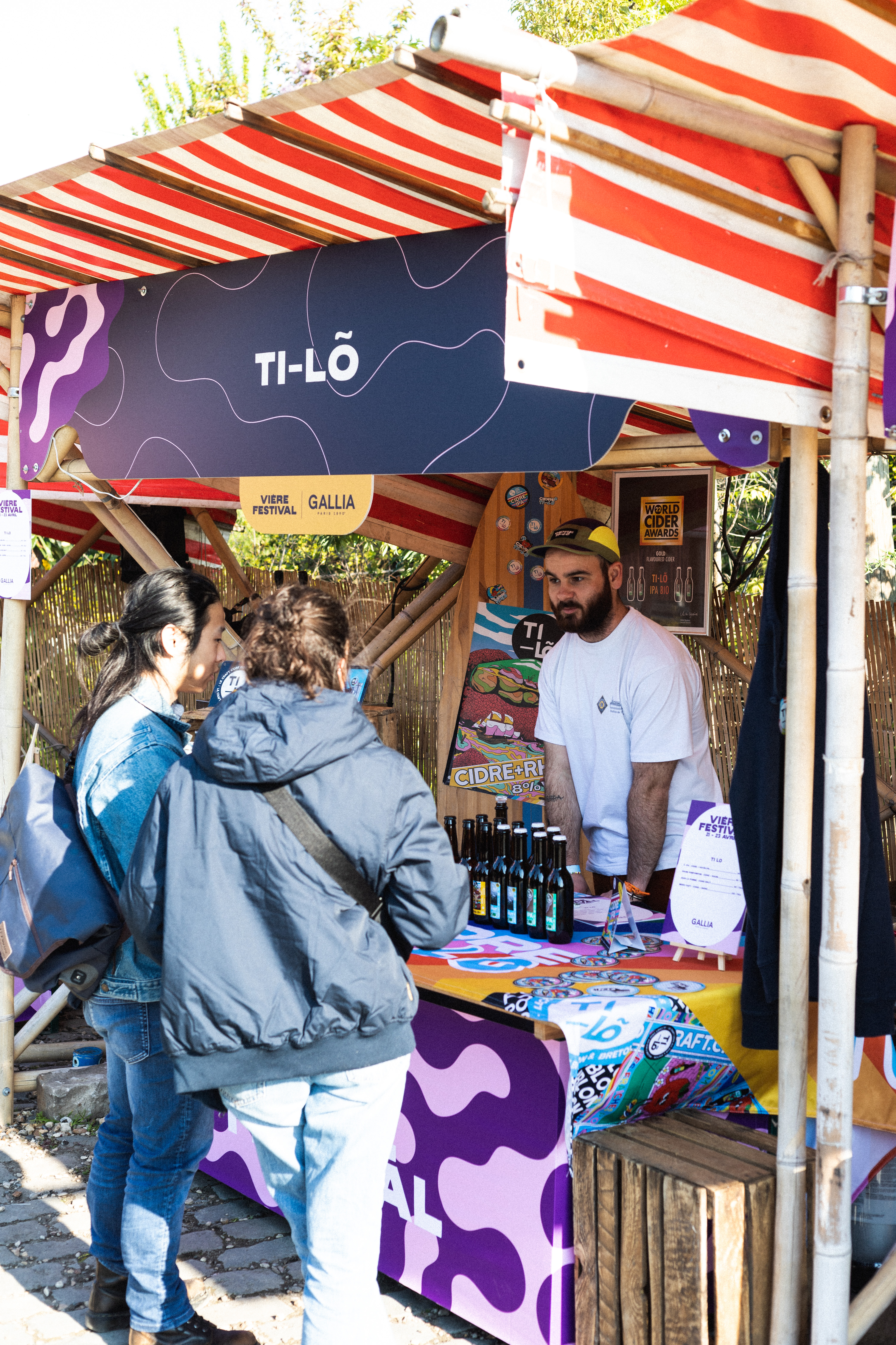Le stand du producteur de cidre Ti-Lõ. Il est debout à droite et discute avec deux personnes en face de lui, à gauche.