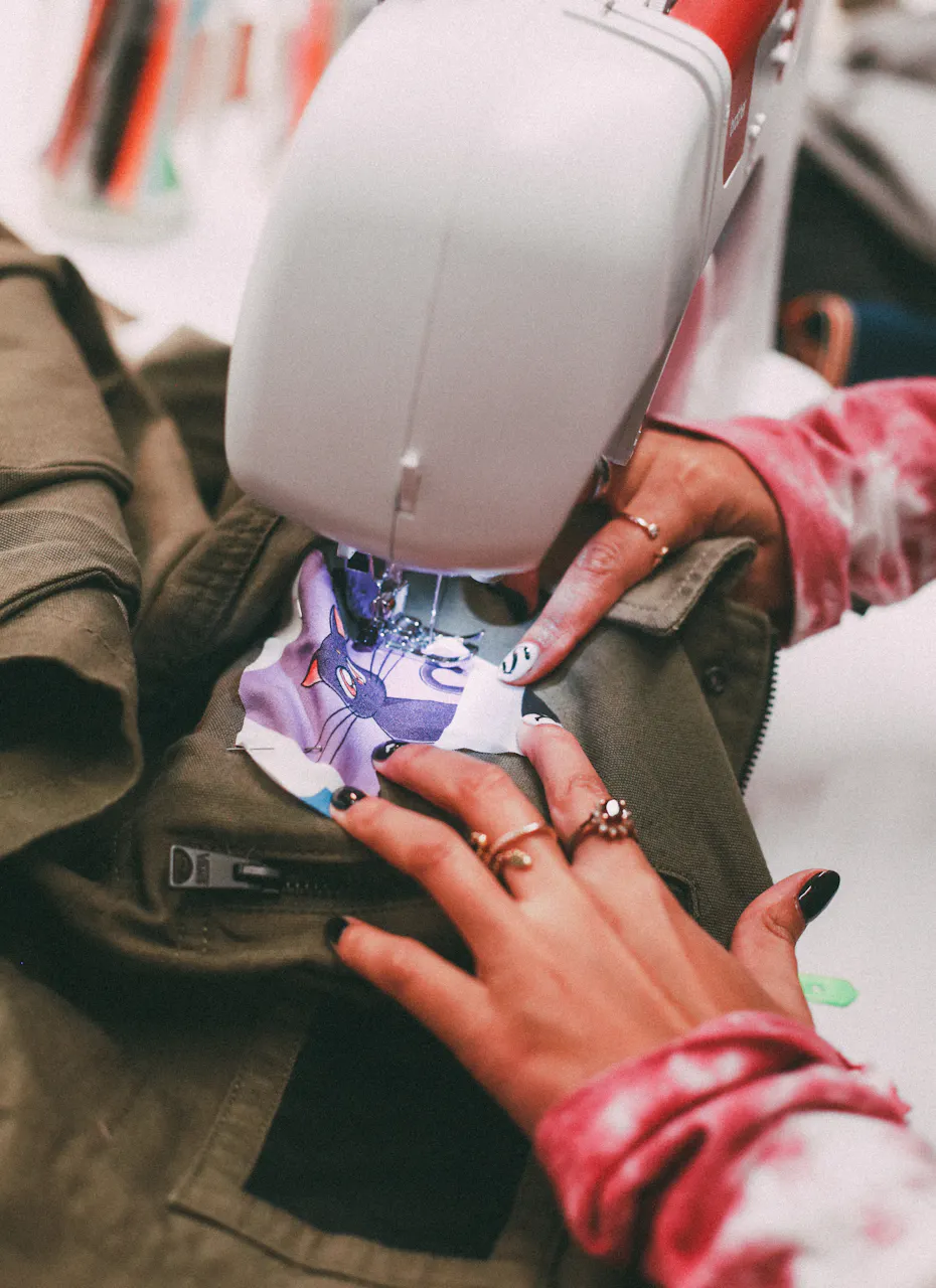 Une personne en train de coudre un patch sur une veste.