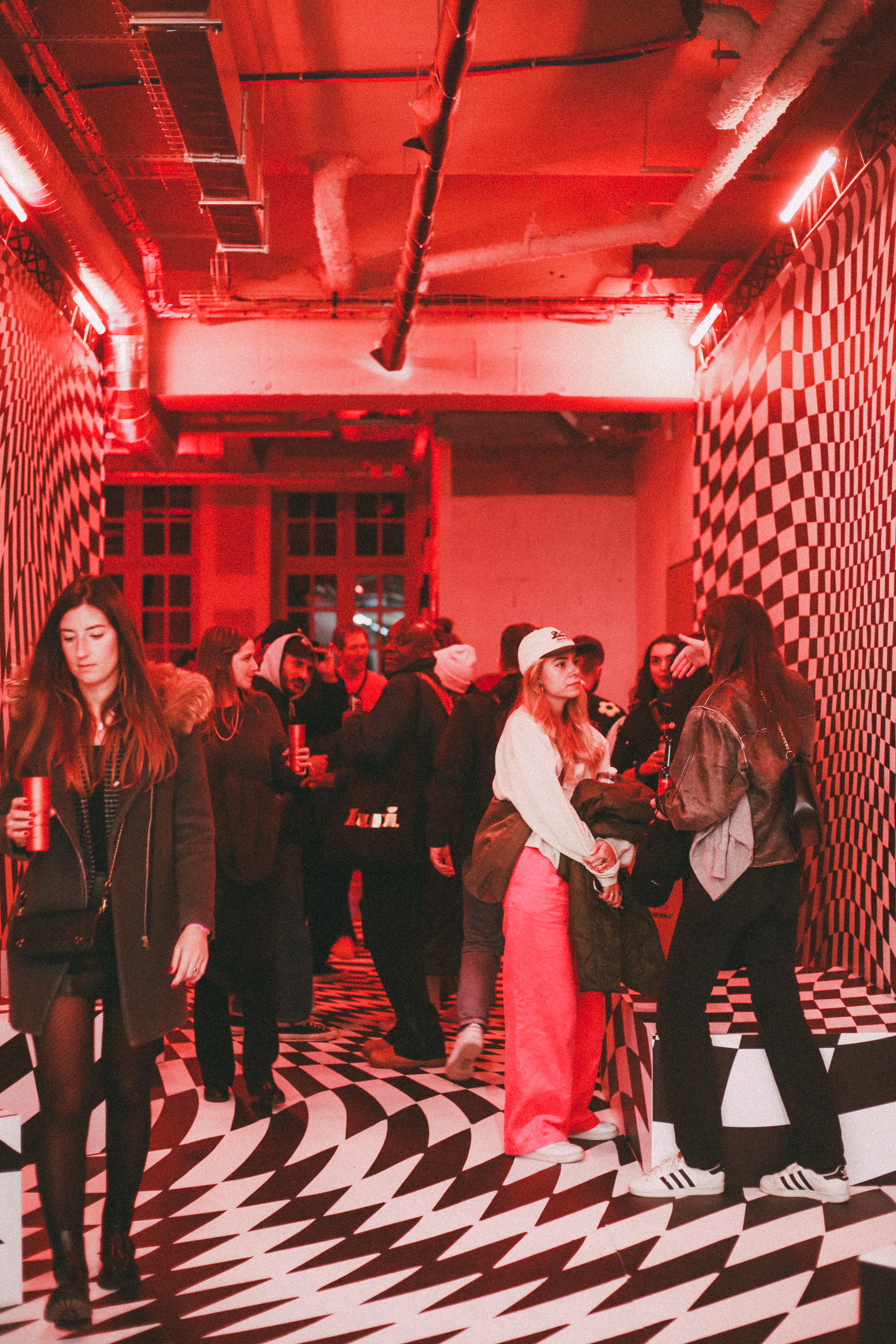 La scénographie du Studio AA : du damier distordu au sol et sur les murs et une lumière rouge.