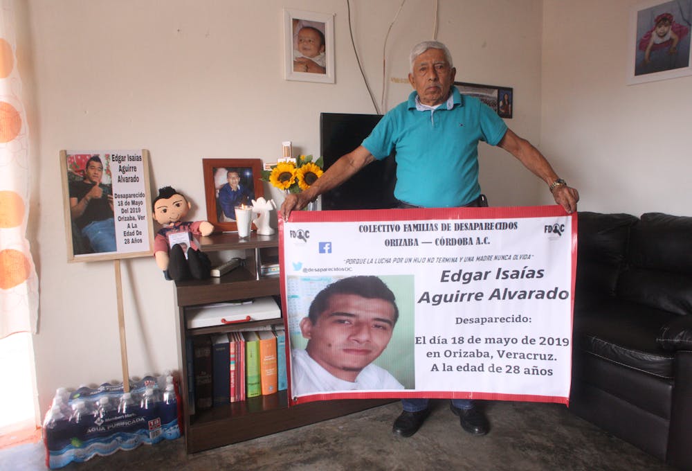 un hombre porta un cartel con la foto de su hijo desaparecido
