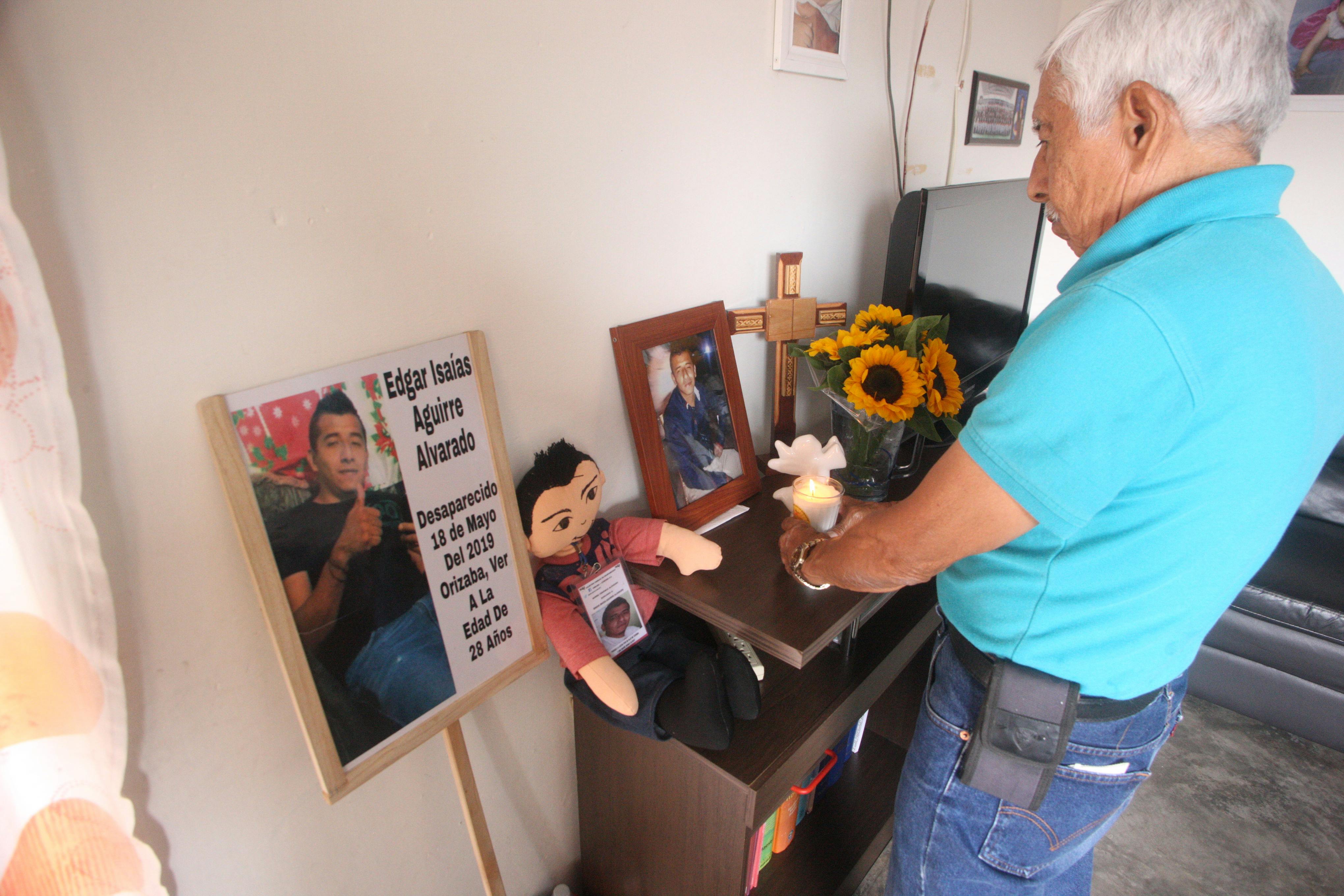 Un anciano coloca una veladora en el altar a su hijo desaparecido