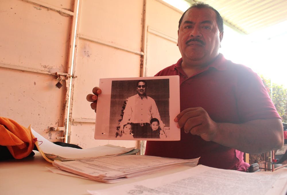 un padre sostiene la foto de su hijo desaparecido
