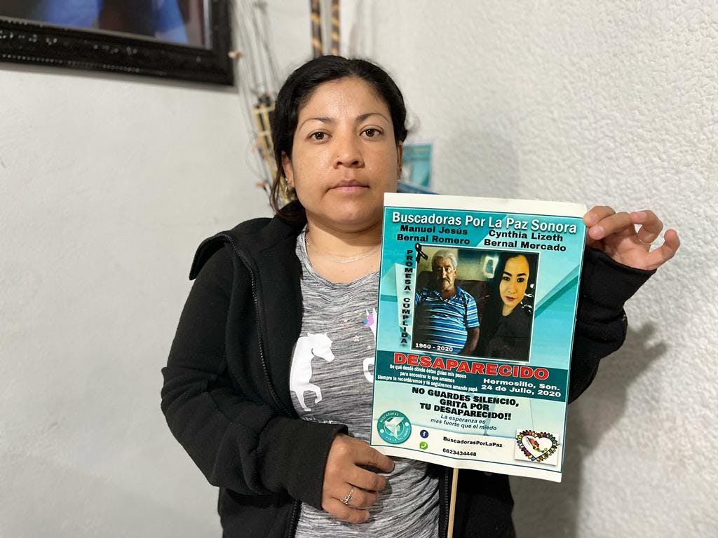 Mujer enseña cartel de su familiar desaparecido