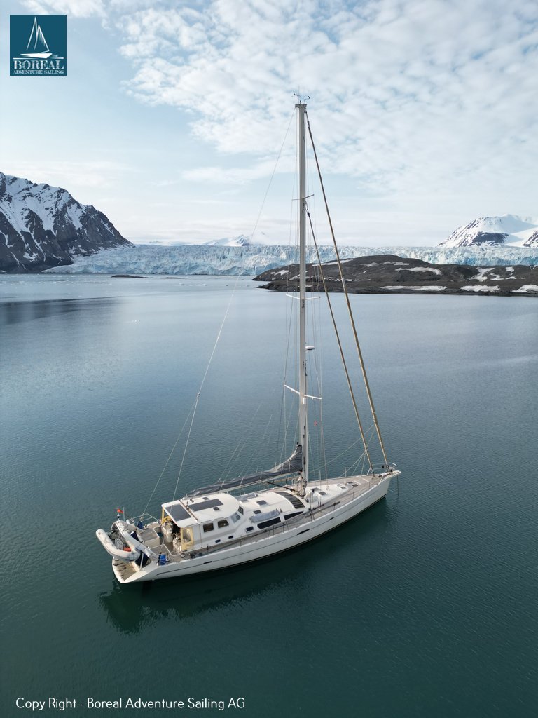 Sail & Explore, Svalbard: drone view of the yacht at anchor, glacier and peaks behind