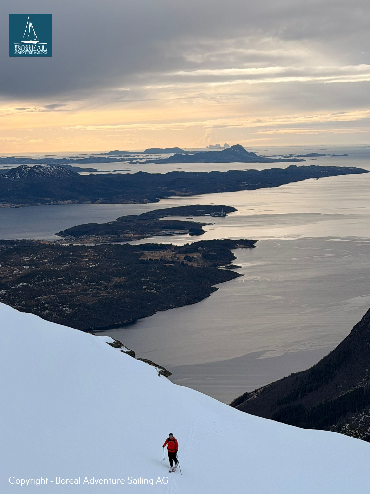 Ski & Sail, Bodø & Lofoten: lone skier high above a fjord and islands in golden light