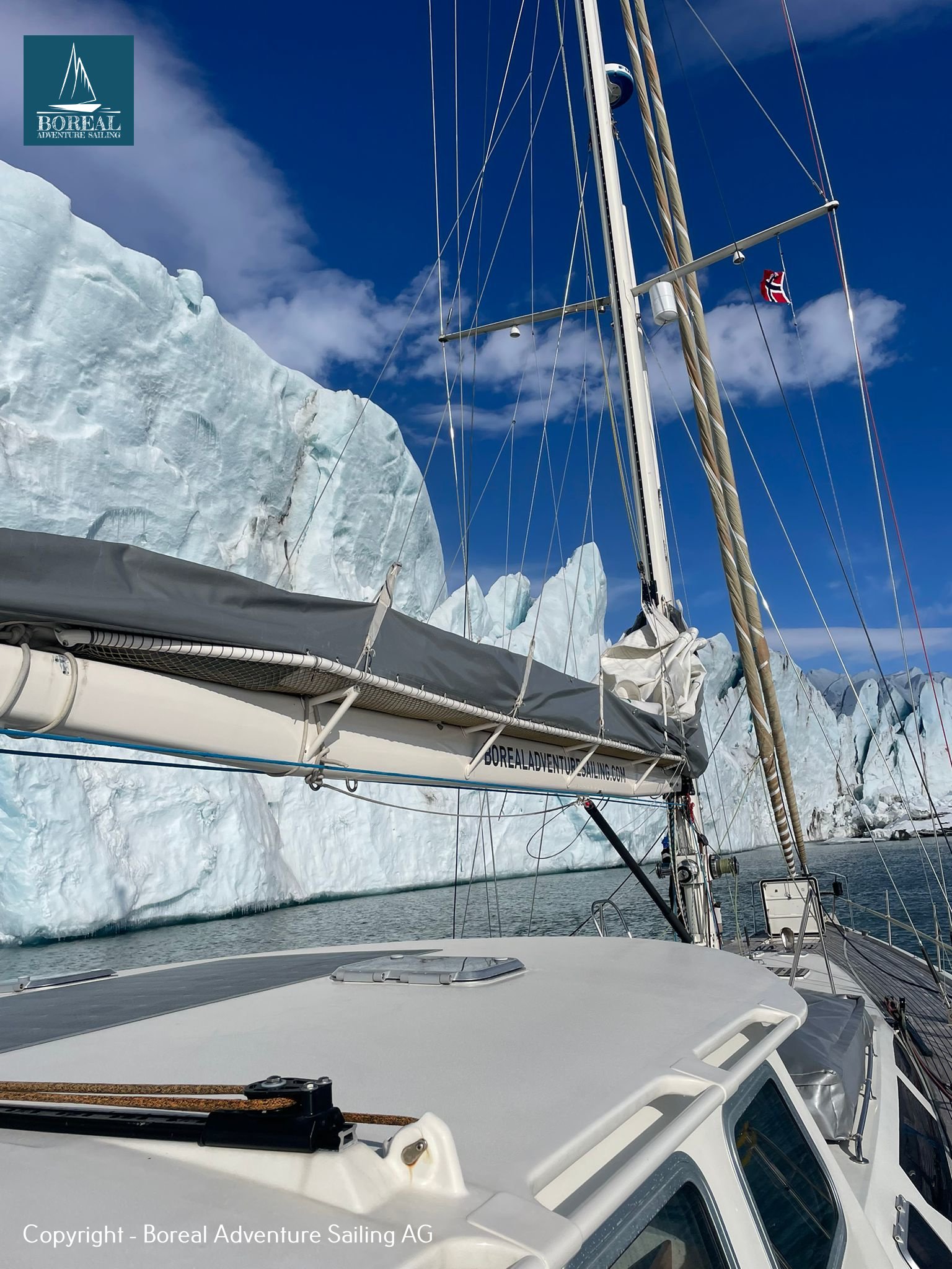 Ski & Sail, Svalbard: yacht deck beside a towering glacier front under blue sky