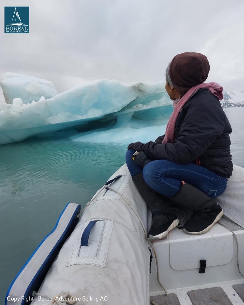 Sail & Explore, Svalbard: guest in the dinghy gazing at a blue iceberg
