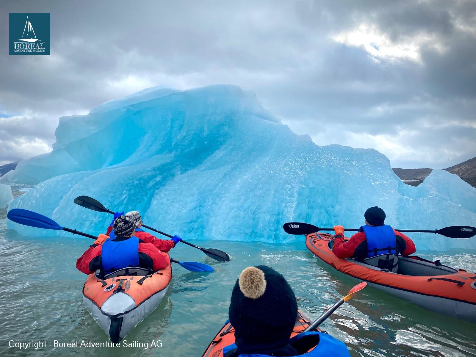 Sail & Kayak, Svalbard: kayakers paddling beside a vivid blue iceberg in Svalbard
