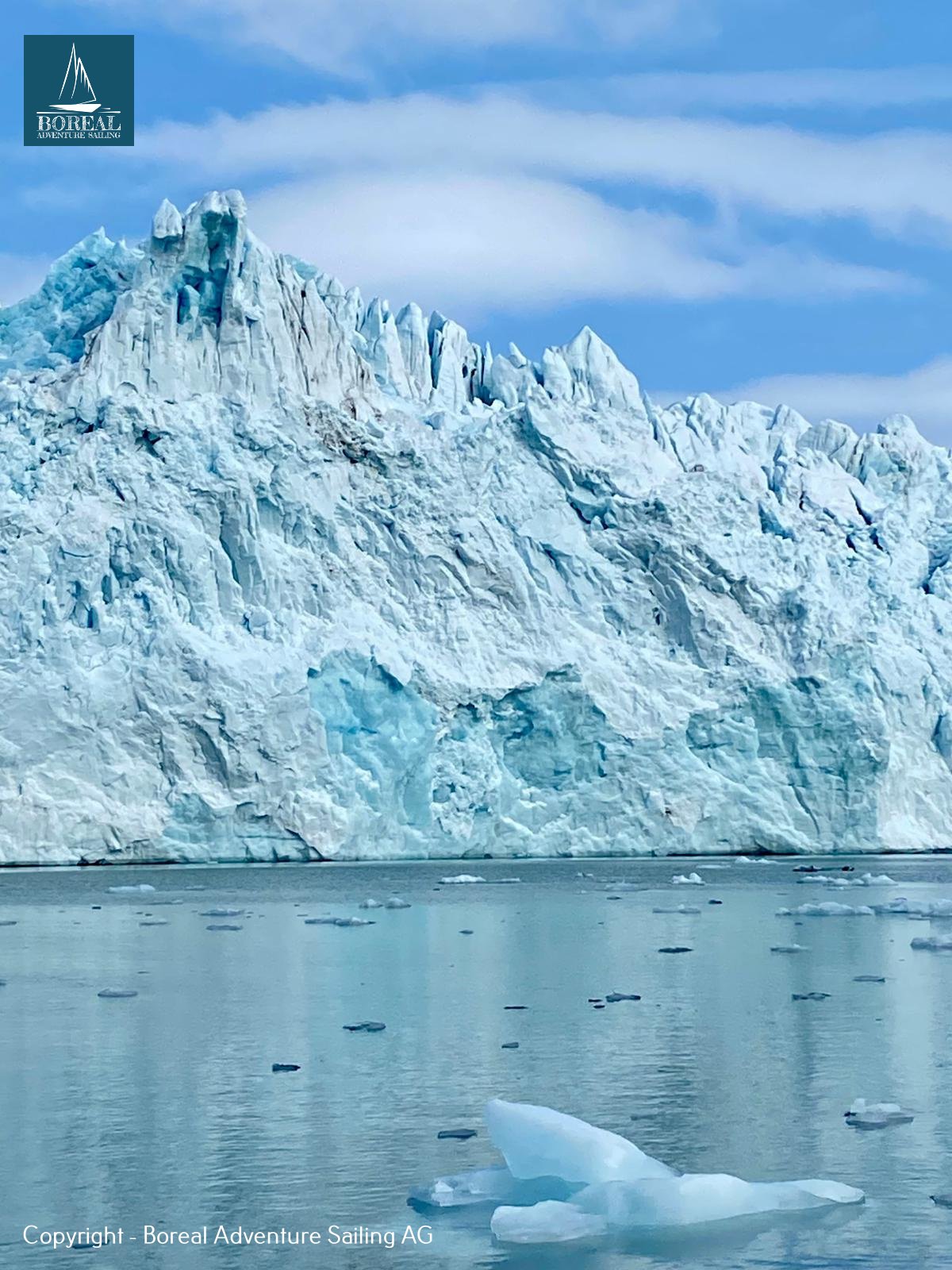 Ski & Sail, Svalbard: towering blue glacier front with floating ice in the fjord