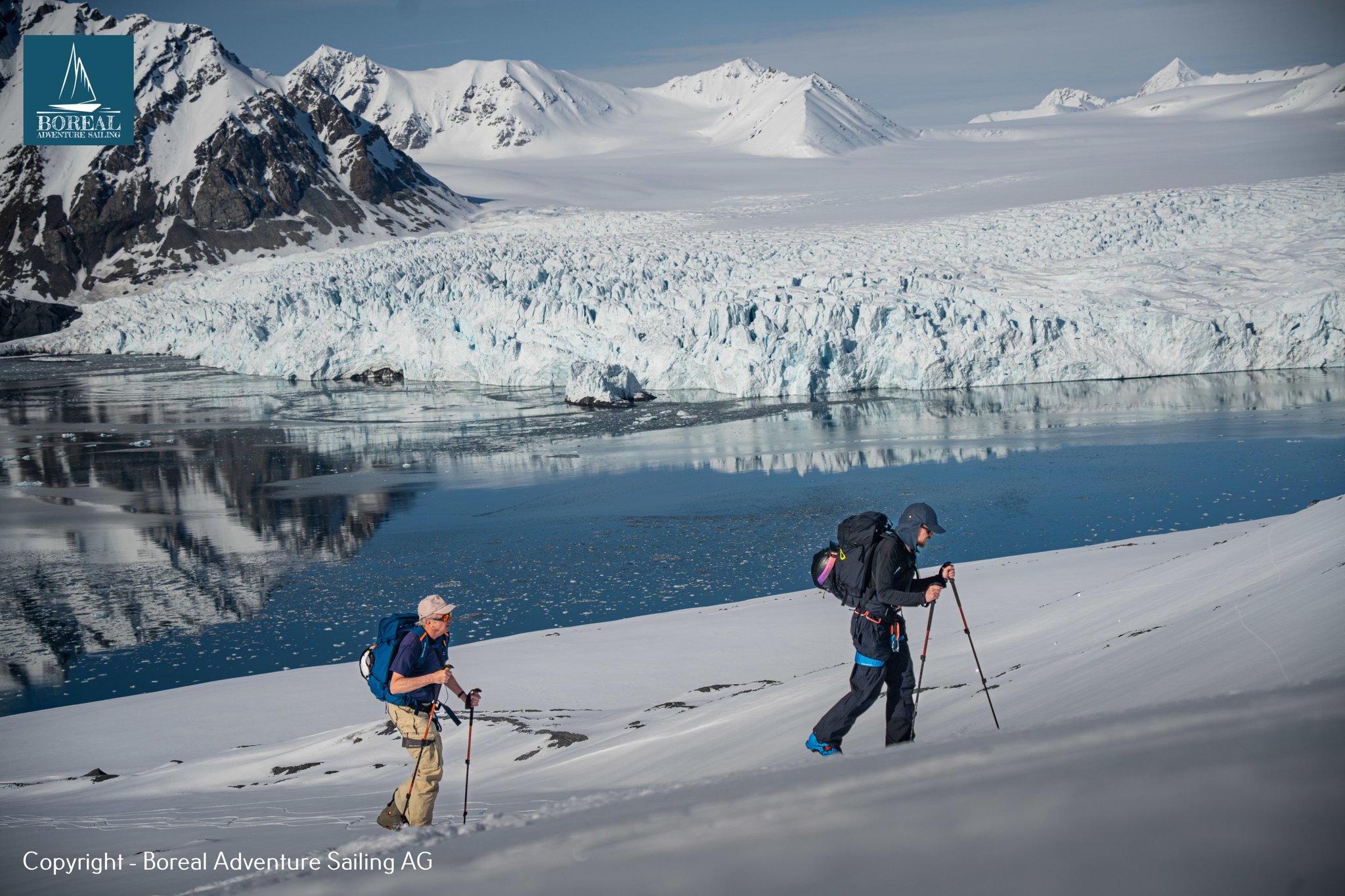 Ski & Sail, Svalbard: two ski tourers skinning in front of a glacier front