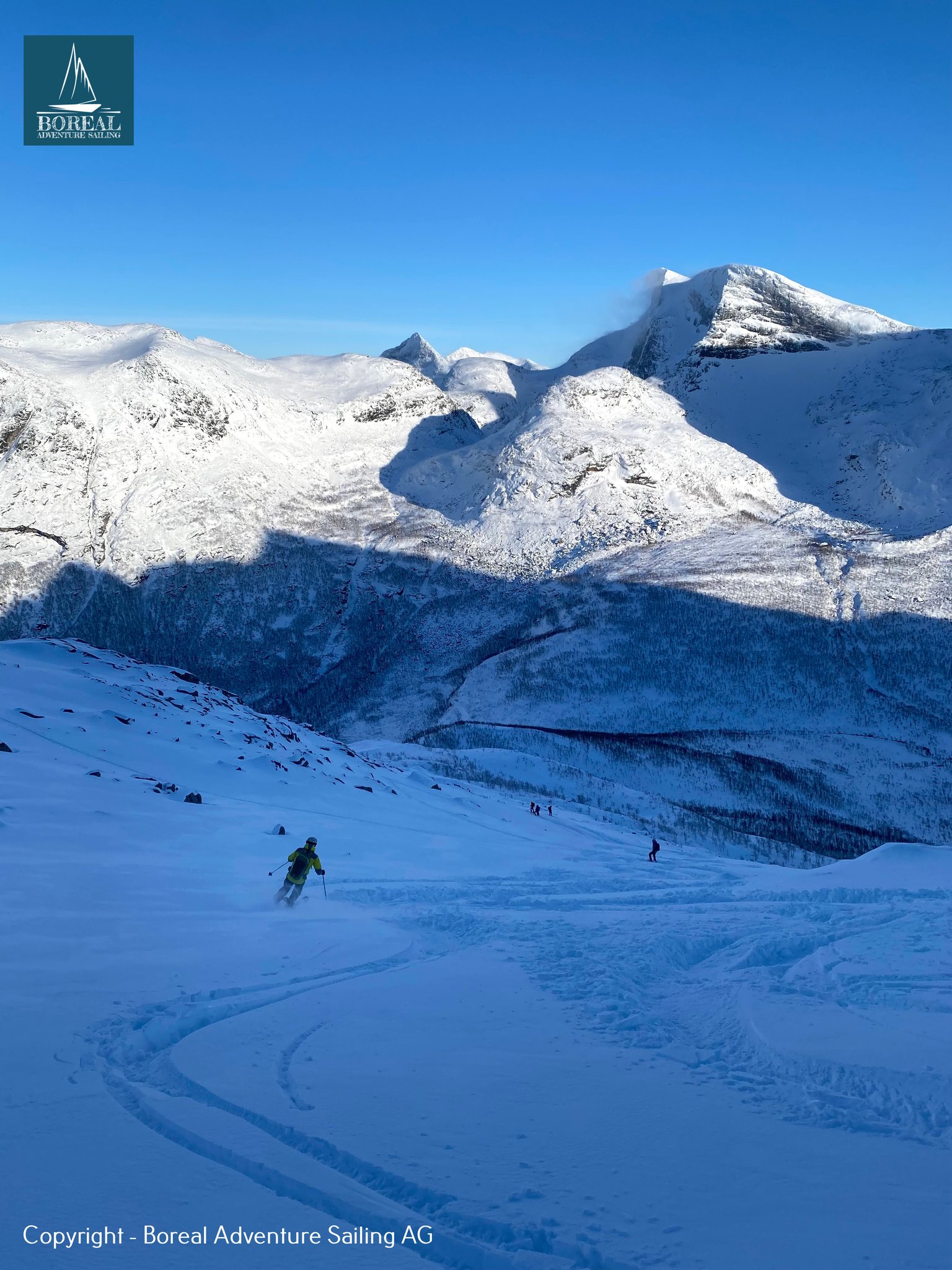 Ski & Sail, Bodø & Lofoten: skier descending a shaded snowfield below sunlit mountains