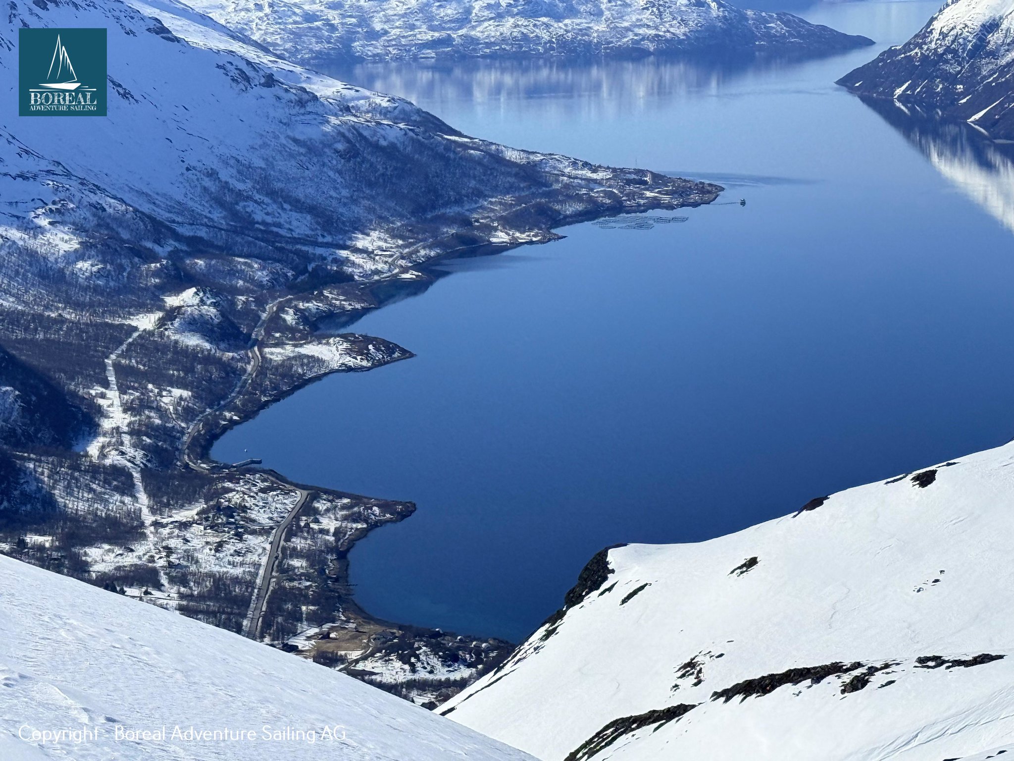 Ski & Sail, Lyngen Alps: steep summit view down to a deep blue fjord and village
