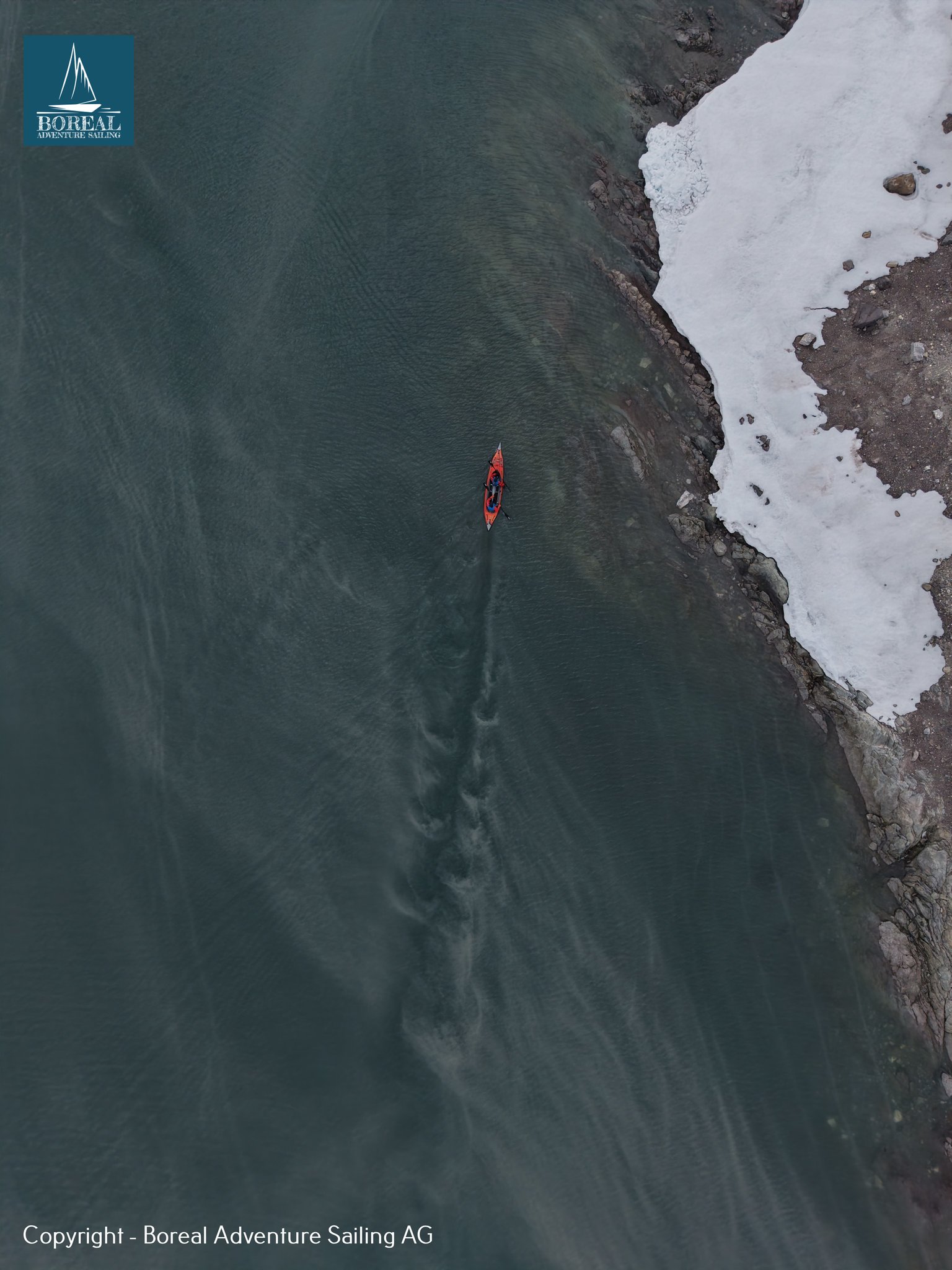 Sail & Kayak, Svalbard: drone view of a lone red kayak along a snowy shoreline
