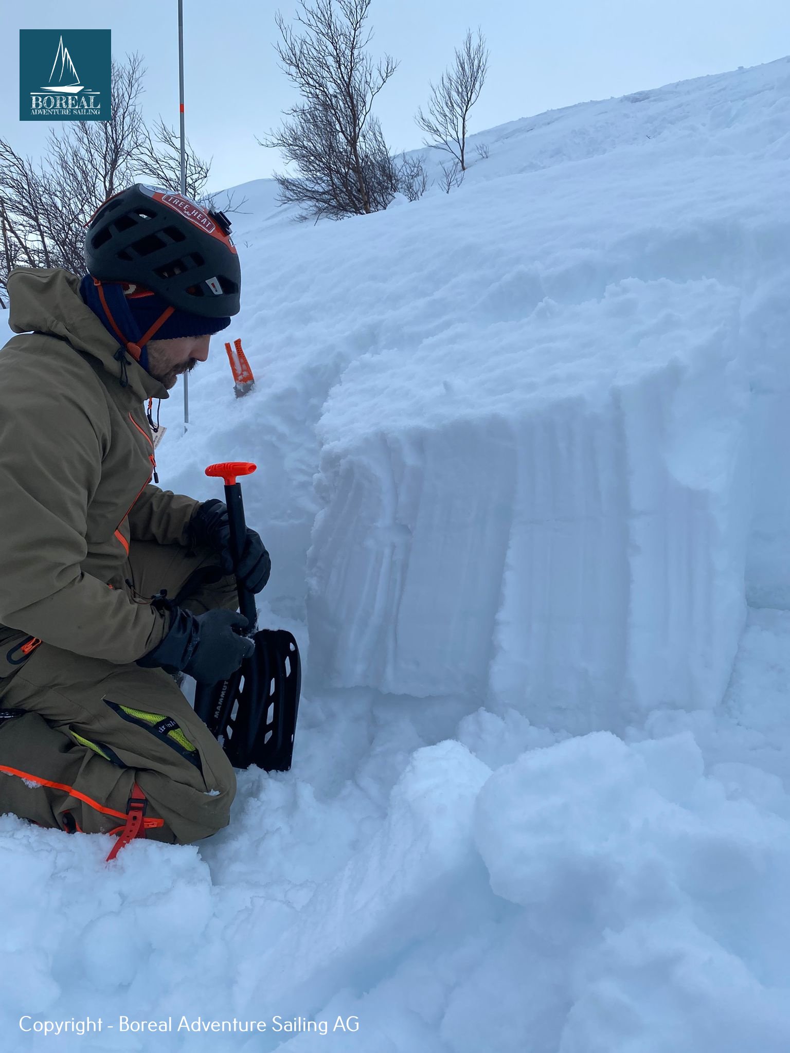 Ski & Sail, Bodø & Lofoten: skier kneeling in a snow pit to assess avalanche conditions