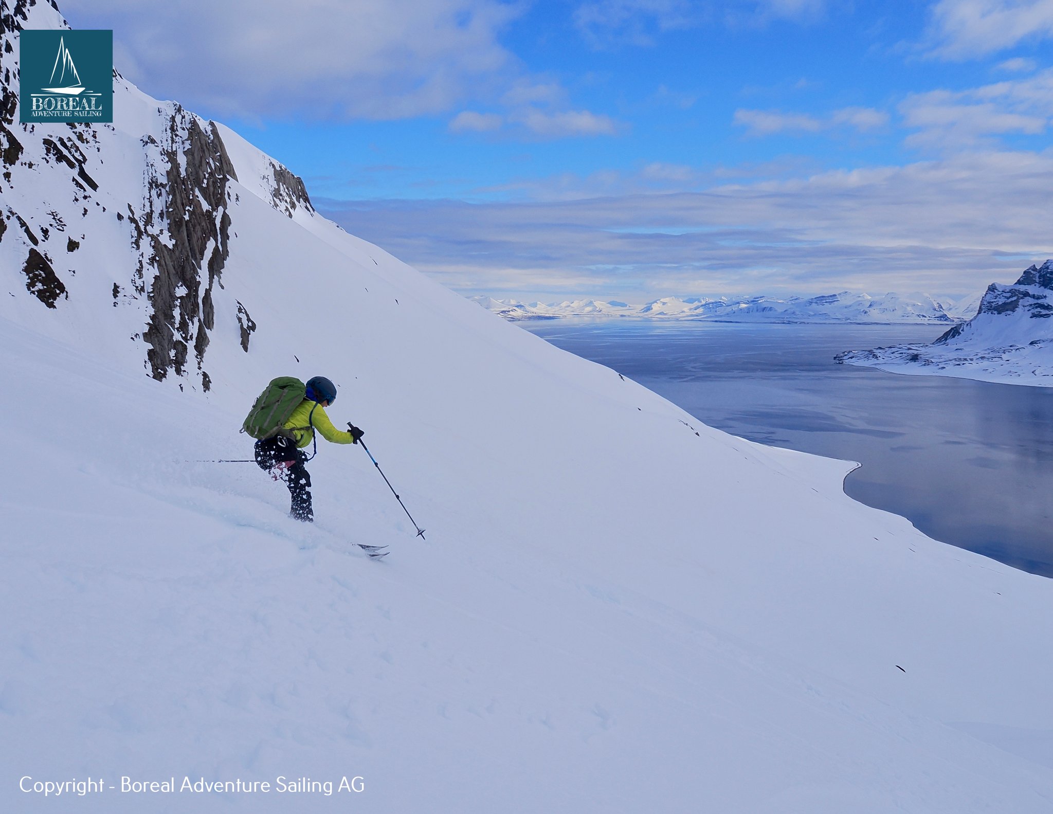 Ski & Sail, Svalbard: skier descending a steep snow slope above the fjord