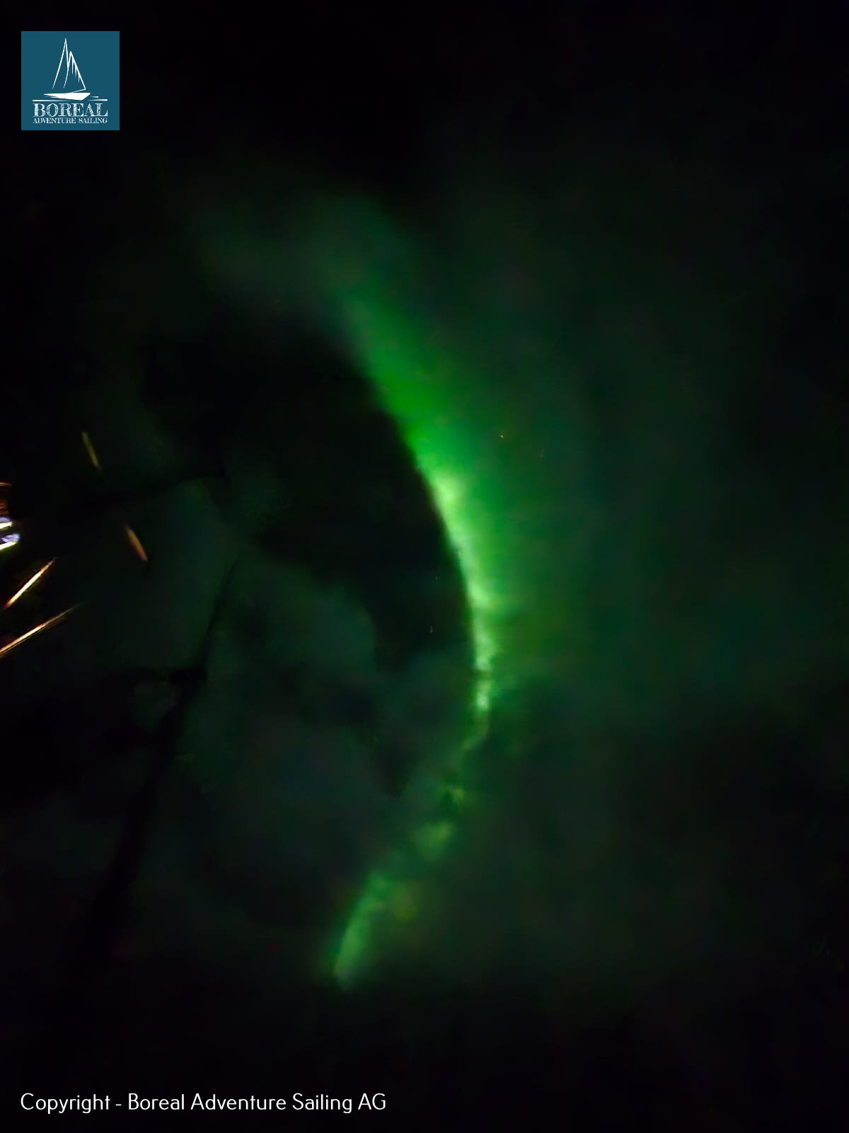 Ski & Sail, Bodø & Lofoten: green northern lights arcing across the dark Arctic night sky