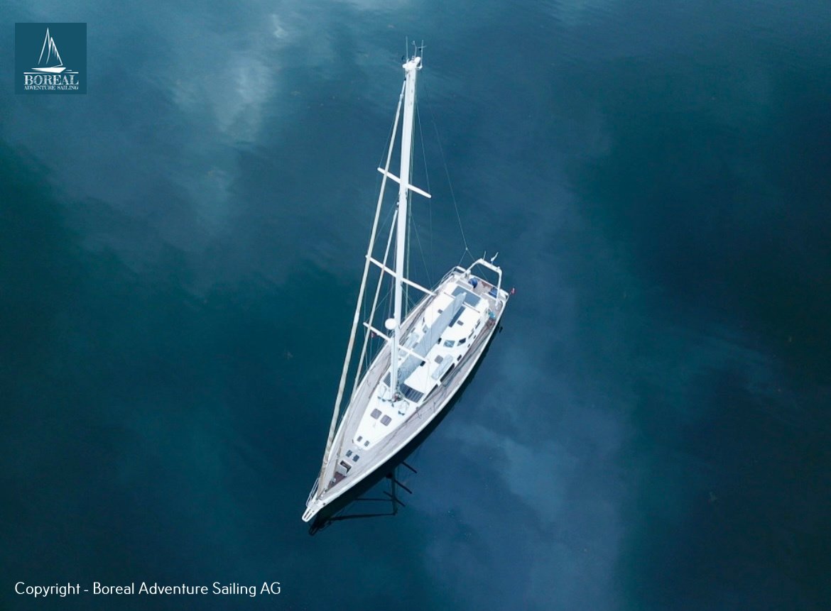 Ski & Sail, Lyngen Alps: aerial view straight down on the sailing yacht at anchor