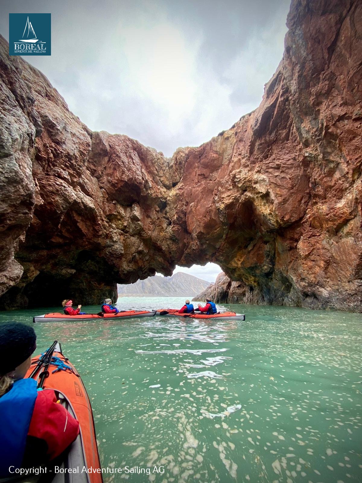 Sail & Kayak, Svalbard: paddler's view of kayaks approaching a towering rock arch