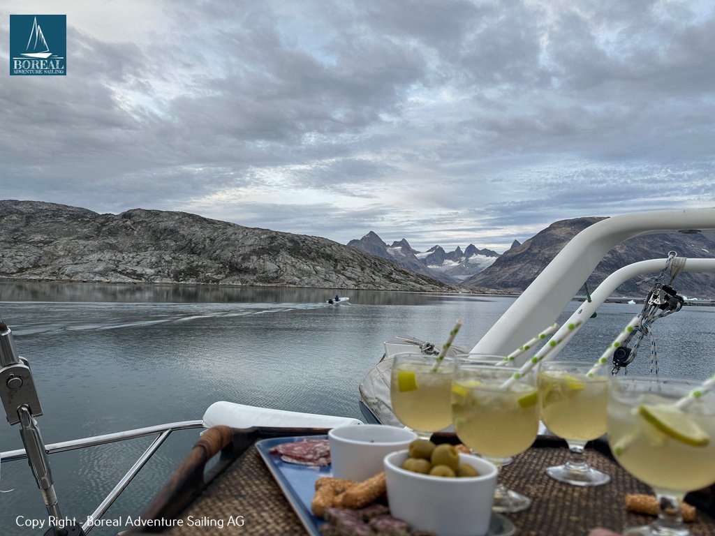 Sail & Explore, East Greenland: aperitif drinks and snacks on deck overlooking a fjord