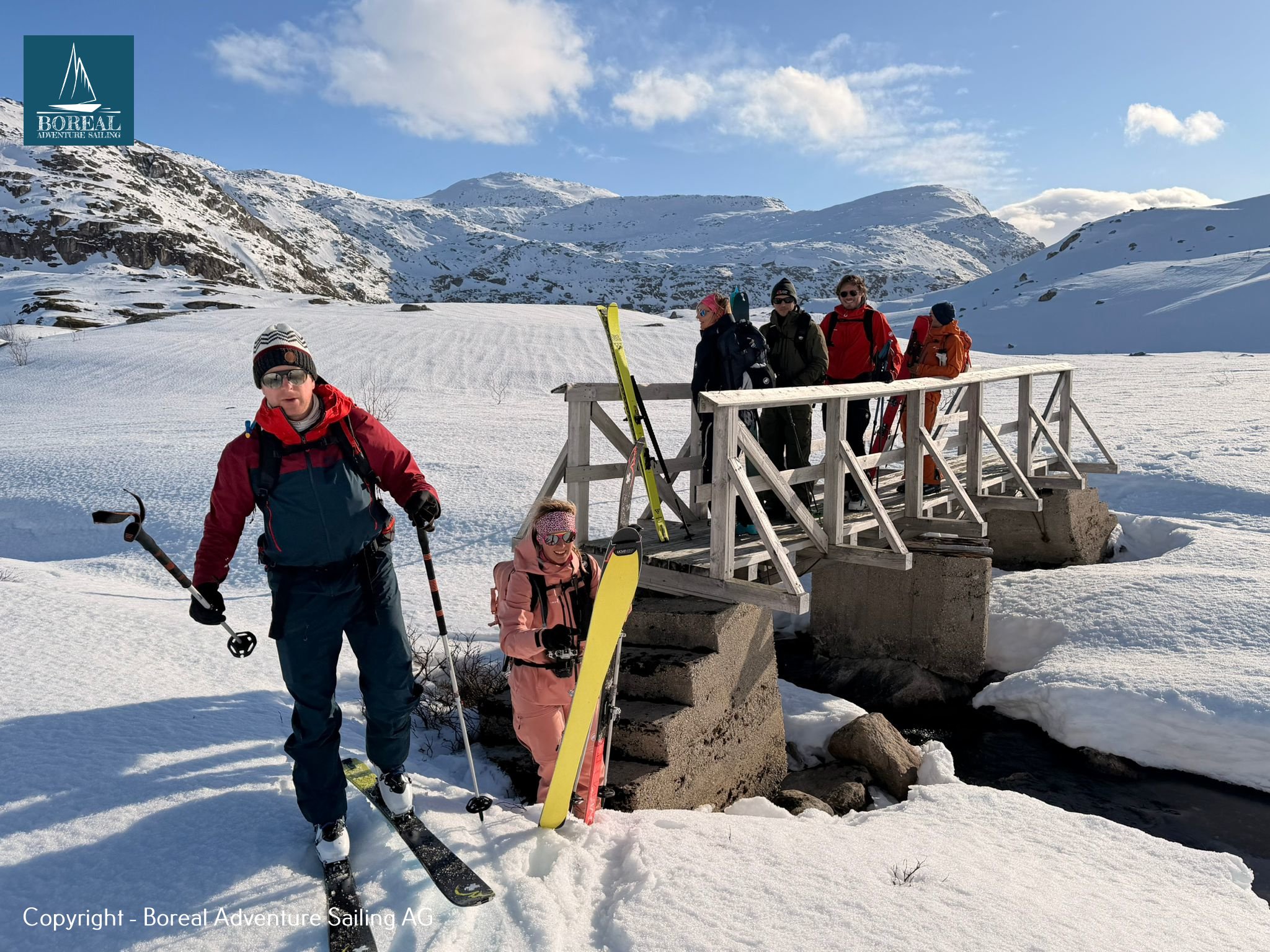 Ski & Sail, Bodø & Lofoten: ski tourers crossing a snowy wooden footbridge on the approach