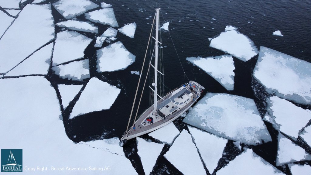 Sail & Explore, Svalbard: aerial view of the sailing yacht among broken sea-ice floes