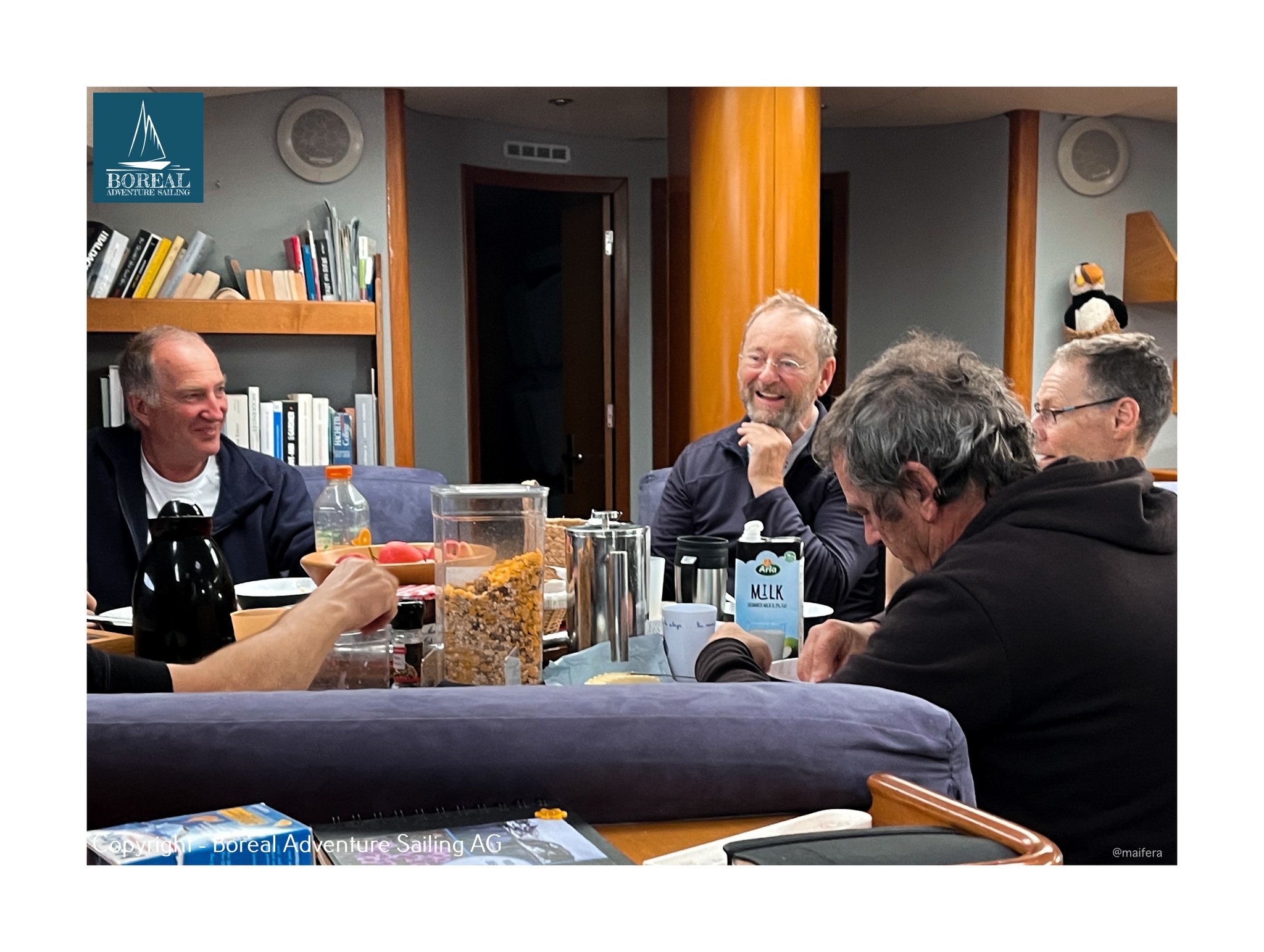 Offshore Sailing: crew laughing together over a meal at the saloon table