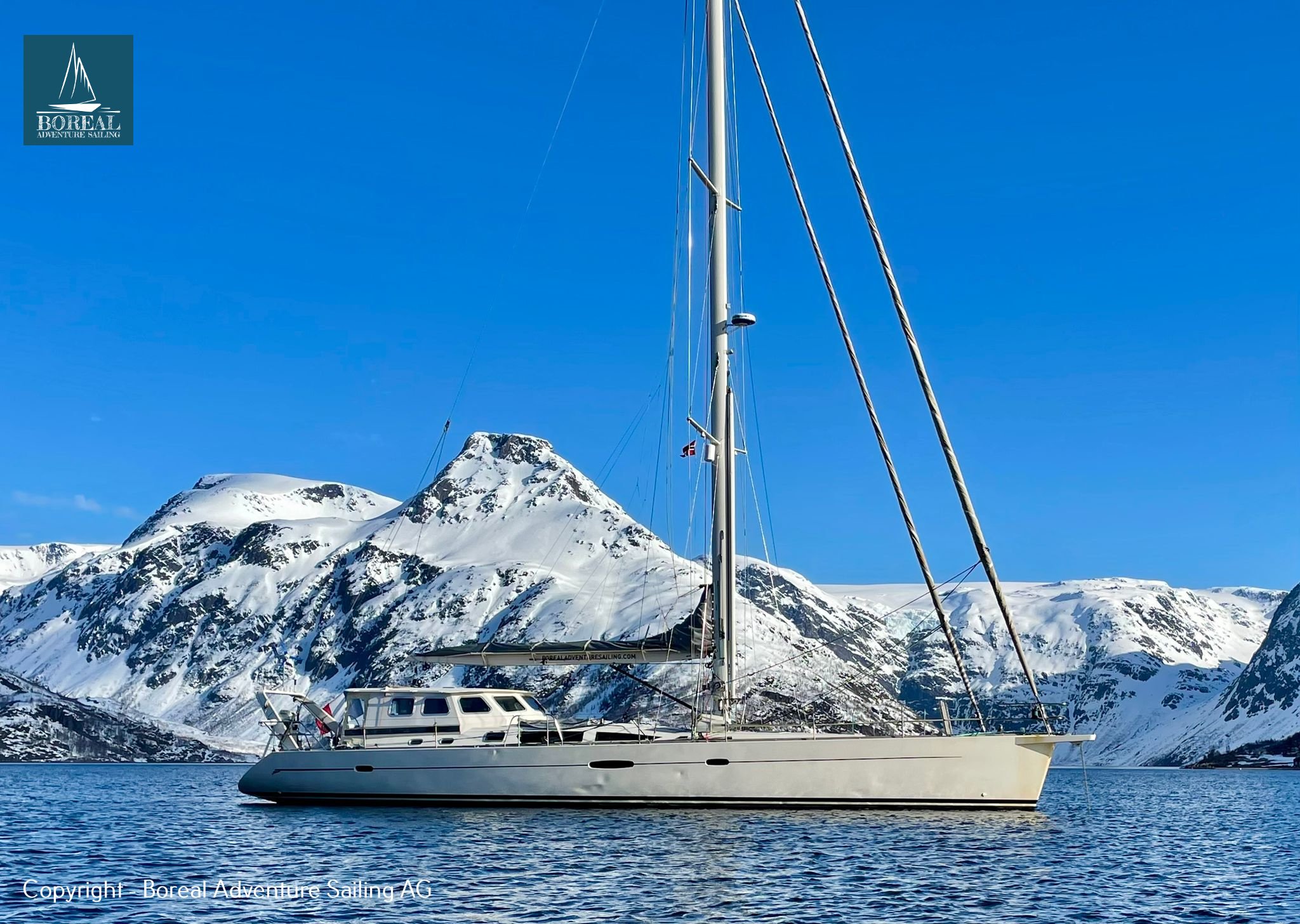 Ski & Sail, Lyngen Alps: sailing yacht at anchor beneath a sharp snow-covered peak