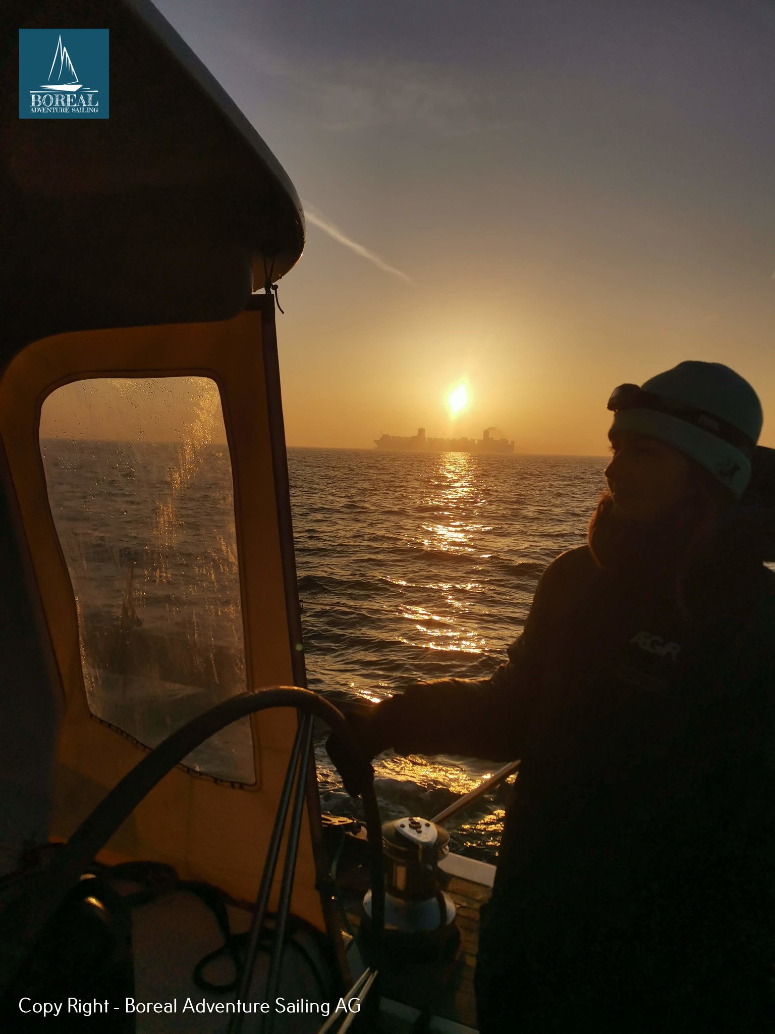 Offshore Sailing: helmsman silhouetted at the wheel, low sun glittering on the sea