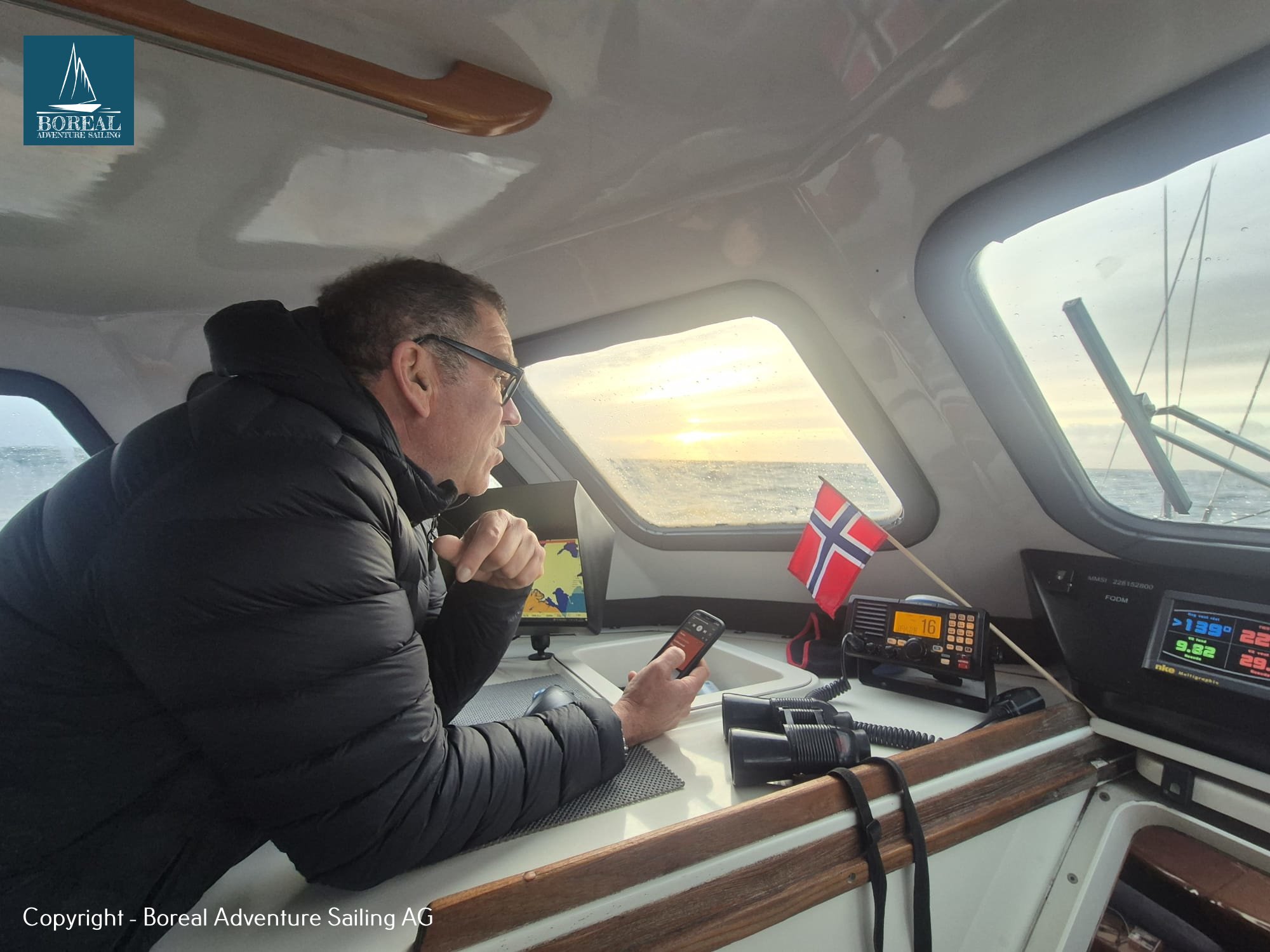Offshore Sailing: crew member at the navigation station beside radio and instruments