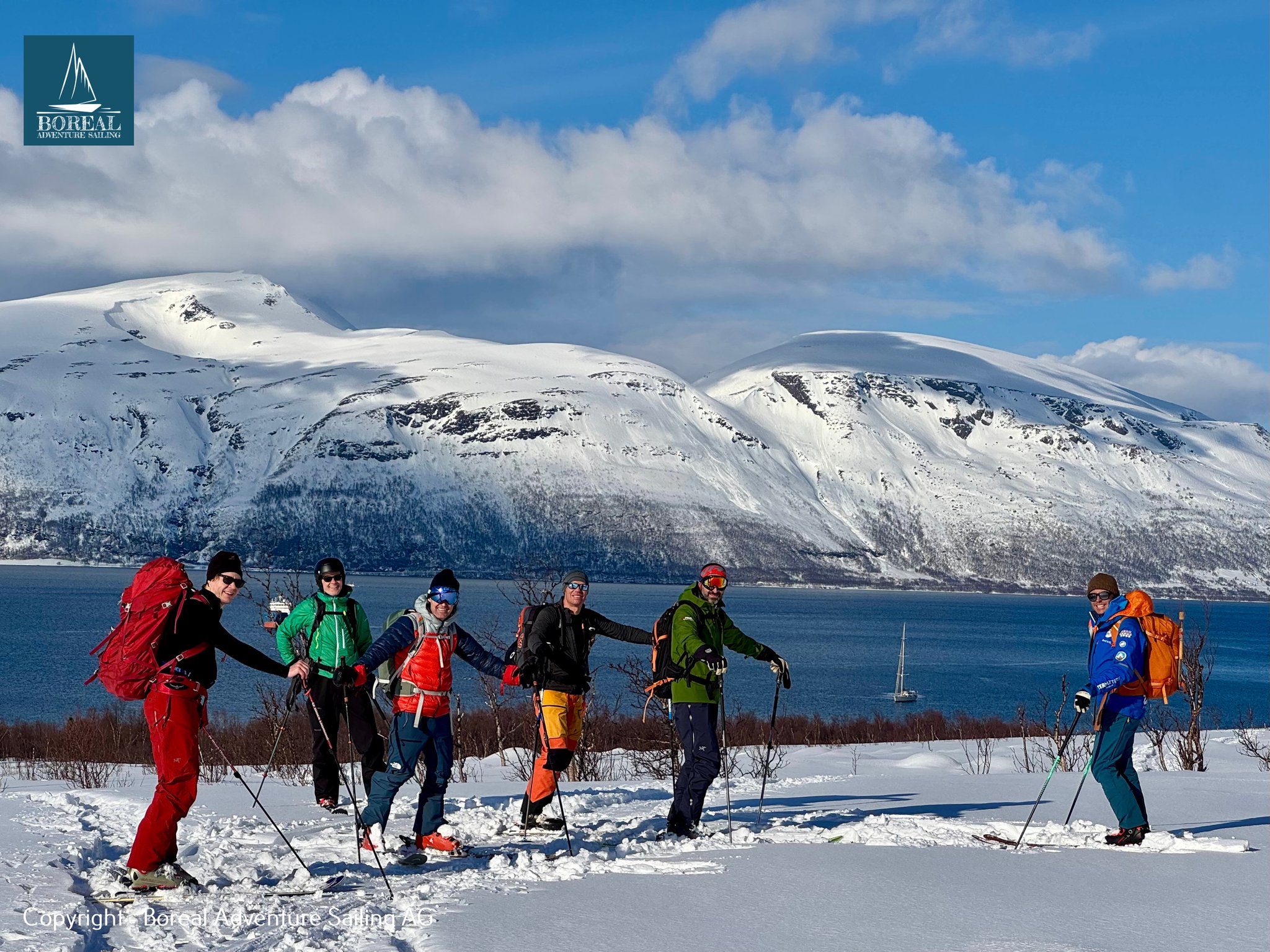 Ski & Sail, Lyngen Alps: ski group setting off by the fjord with the yacht behind