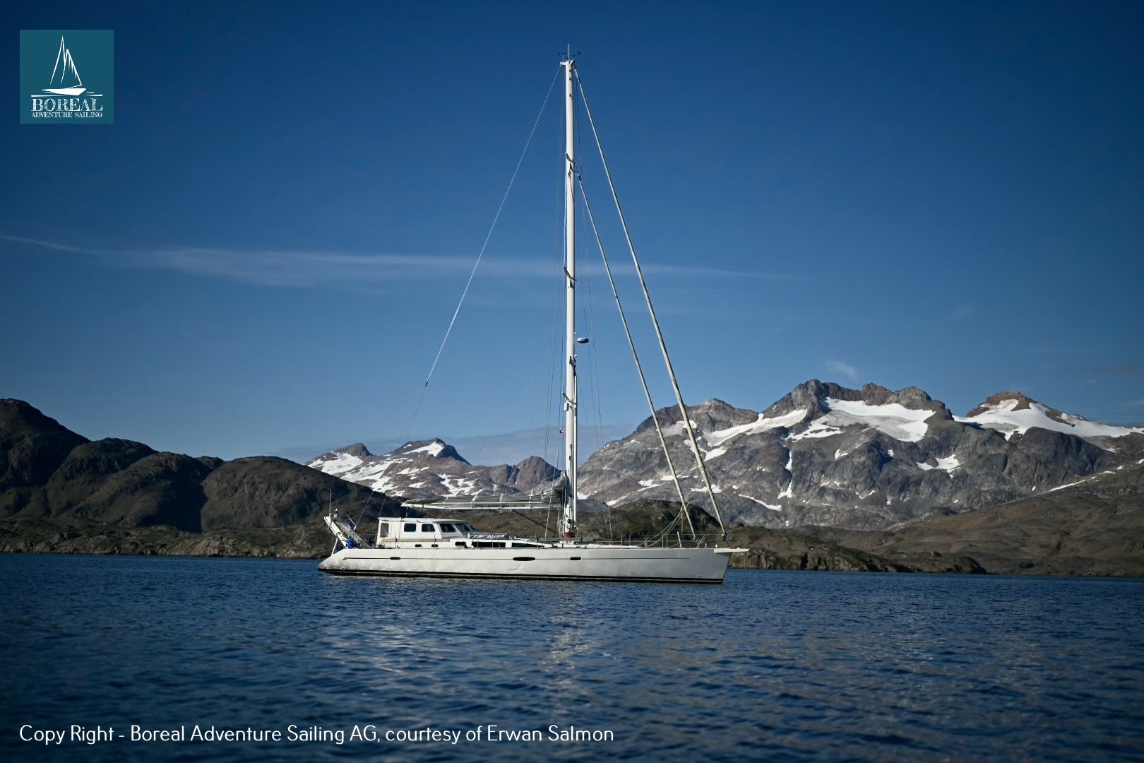Sail & Explore, East Greenland: sailing yacht at anchor below snow-capped East Greenland peaks