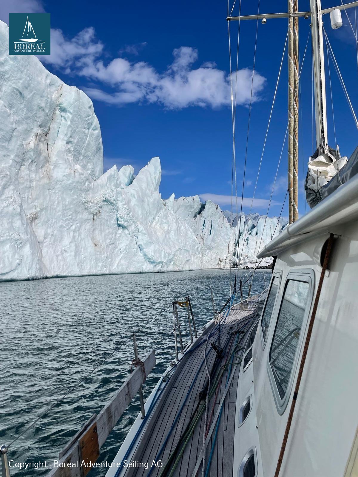 Offshore Sailing: side deck of the yacht beside a towering Arctic glacier front