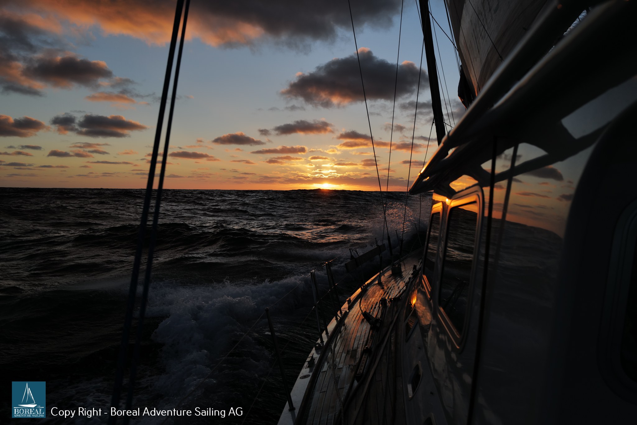 Offshore Sailing: sun setting on the horizon, seen from the heeling deck