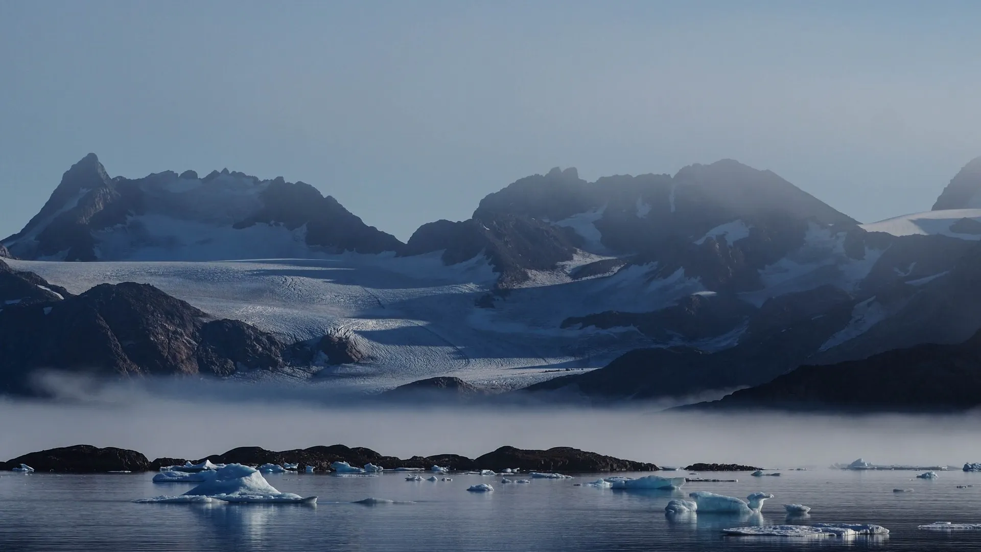 Voile & Exploration, Groenland de l’Est : sommets et glaciers dans la brume au-dessus d’une baie parsemée de glaces