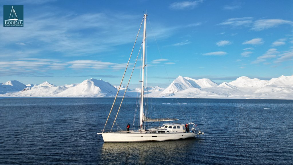 Ski & Sail, Svalbard: sailing yacht at anchor below a range of snowy peaks