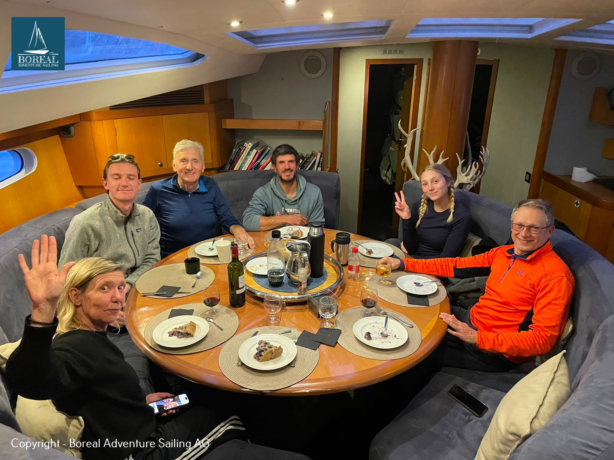 Sail & Explore, East Greenland: guests sharing dinner around the saloon table on board