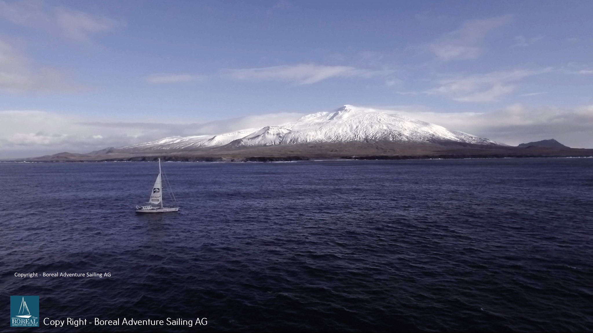 Offshore Sailing: sailing yacht below the snow-capped Snæfellsjökull volcano in Iceland