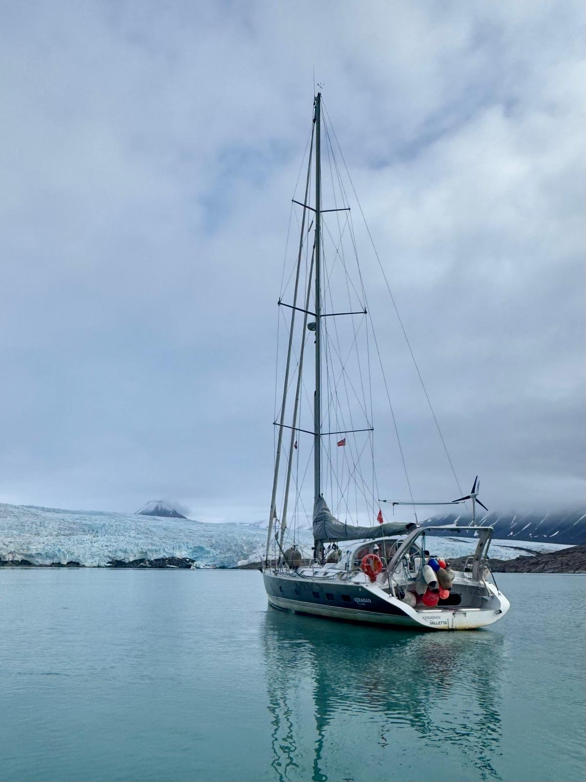 Sail & Explore, Svalbard: sailing yacht at anchor in front of a glacier, reflected in calm water