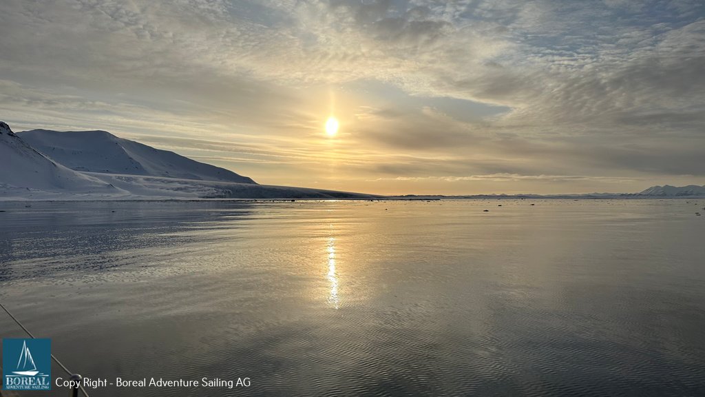 Sail & Explore, Svalbard: midnight sun low over a calm fjord and mountains