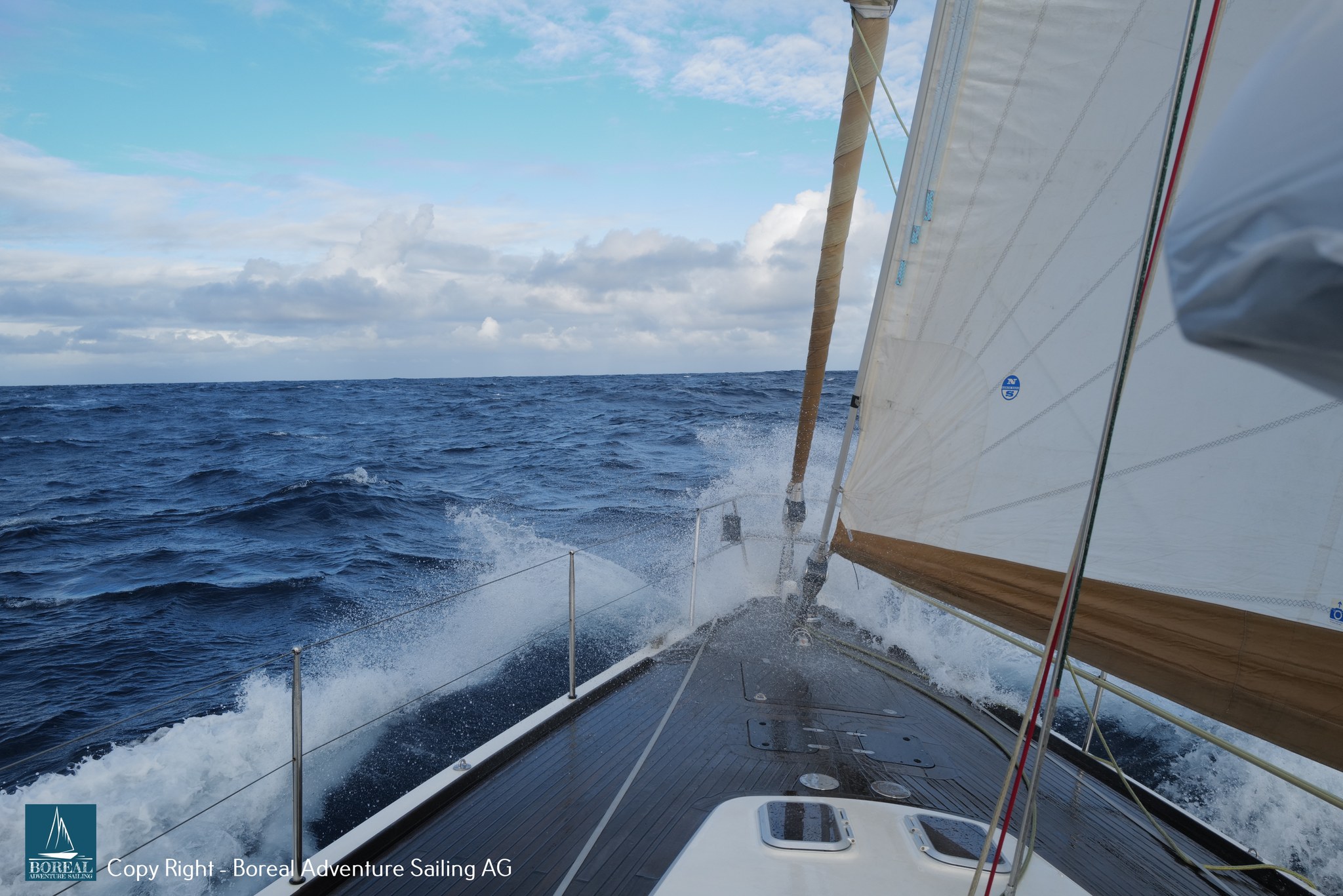 Offshore Sailing: yacht heeled hard, the bow wave breaking over the rail on a blue sea