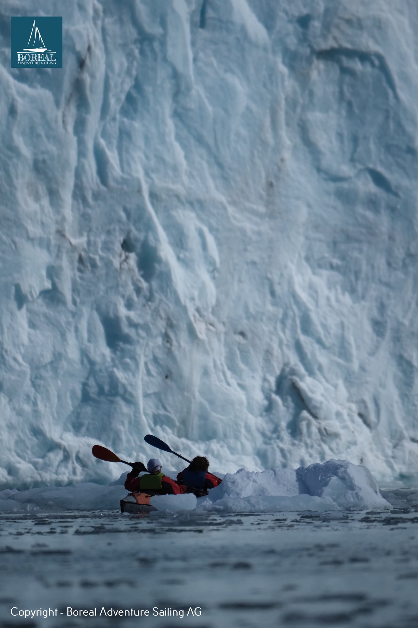Sail & Kayak, Svalbard: tandem kayak dwarfed by a towering wall of glacier ice