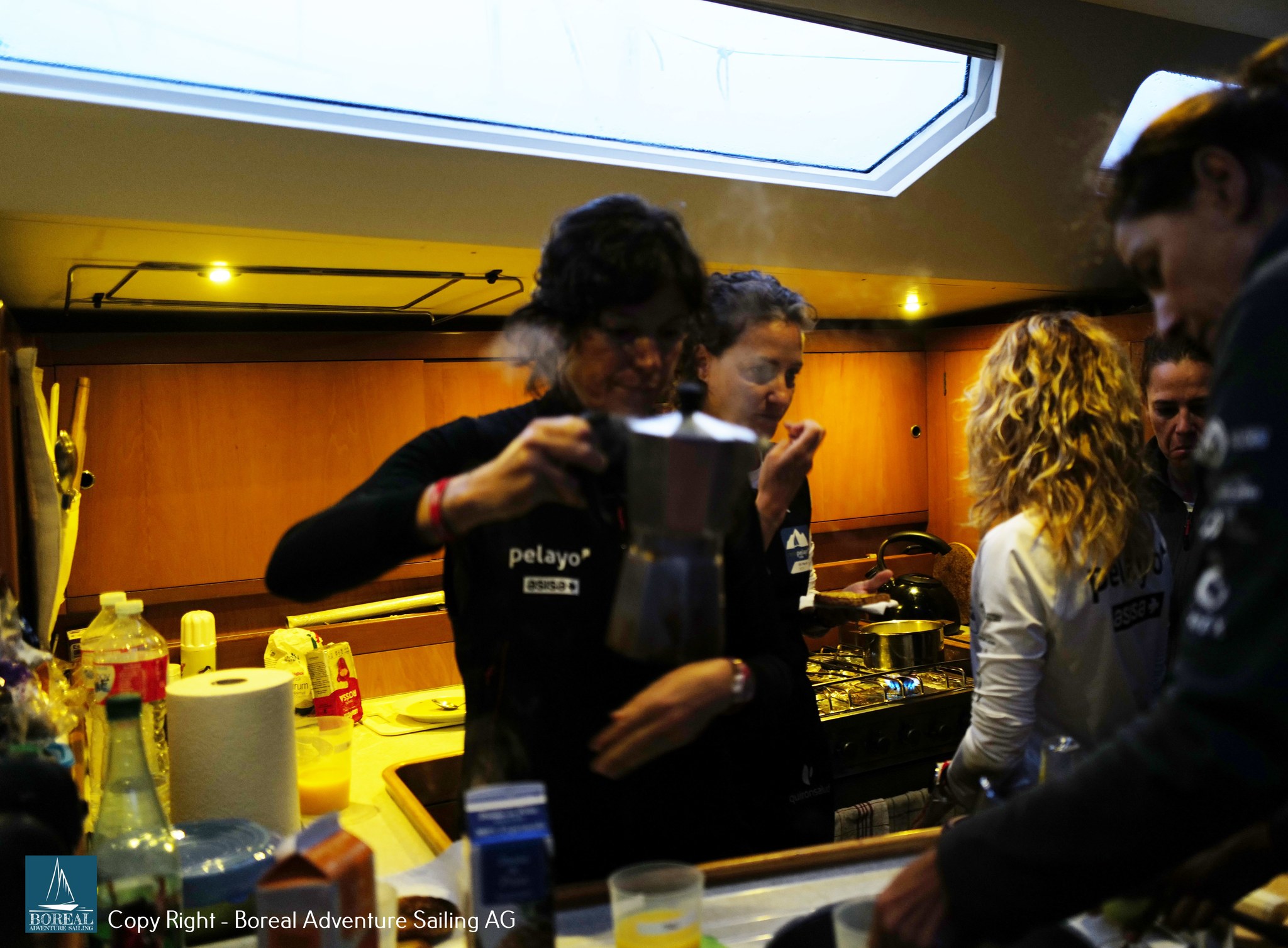 Offshore Sailing: crew making coffee in the warmly lit galley below deck
